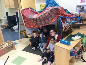Preschoolers building a fort together in the classroom