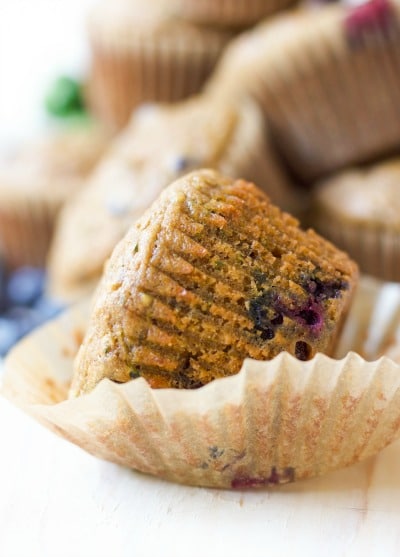 Muffin in a wrapper with blueberries.