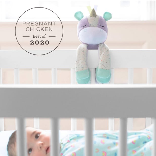 unicorn soother clipped onto the side of a white baby crib
